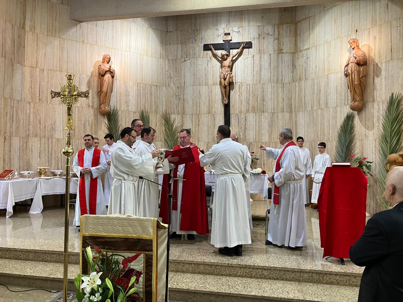 En la imagen, se ve a los sacerdotes participantes en la primera celebración del domingo de ramos, ayudados por los acólitos, prepárandose para la bendición de las palmas y las ramas de olivo en el altar de la capilla del colegio Esclavas de María.